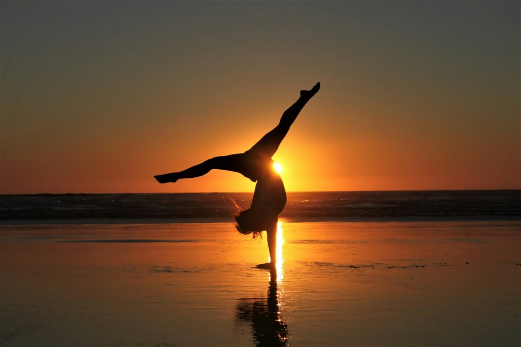 Frau macht Yoga-Pose während Sonnenuntergang während gemafreie Meditationsmusik erklingt